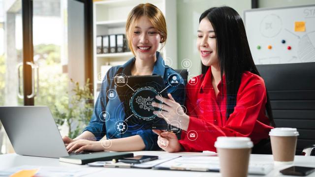 Two women working on a computer, using artificial intelligence. Photo credit: iStock/Thicha Satapitanon.
