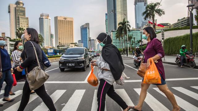 Pedestrians toting their groceries crossing a street in Indonesia.