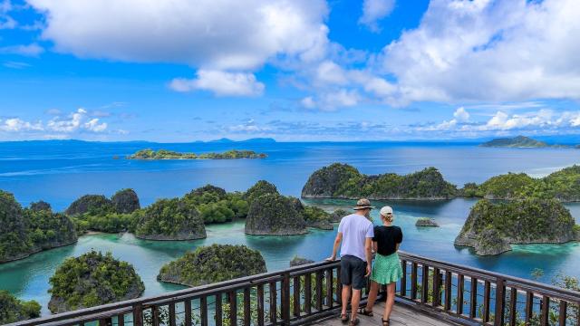 Tourists taking photos of a panoramic view of islands in Raja Ampat. 