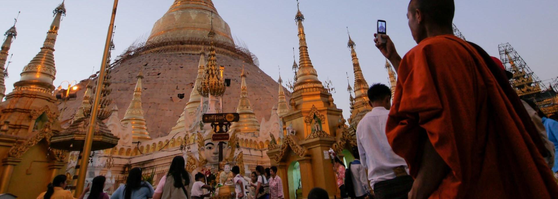 A monk takes a photo of a temple with his mobile phone. Photo credit: ADB.