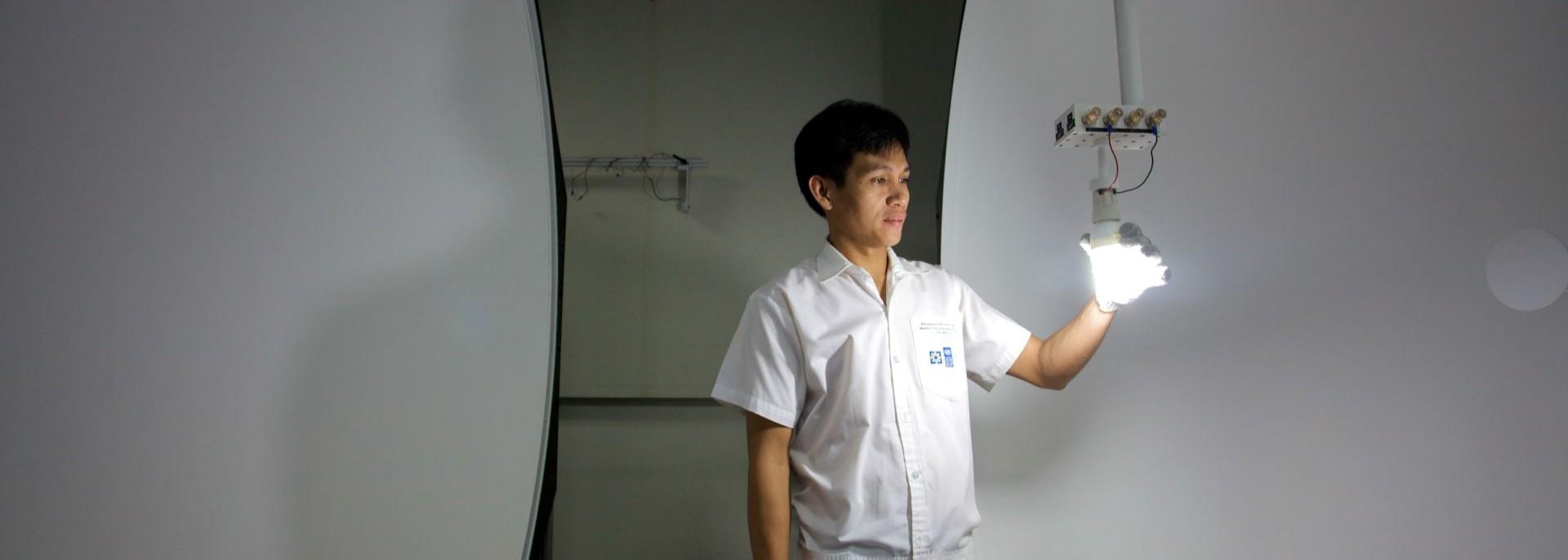 A man tests a ligh bulb for energy efficiency. Photo credit: ADB.